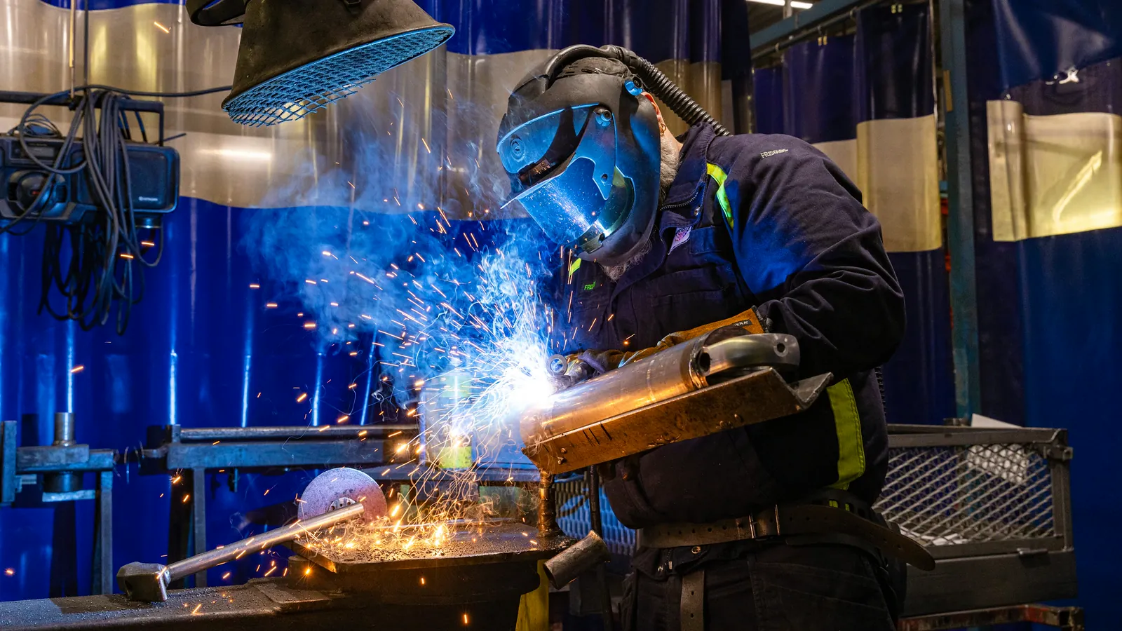 Welder at work with sparks flying off the bench